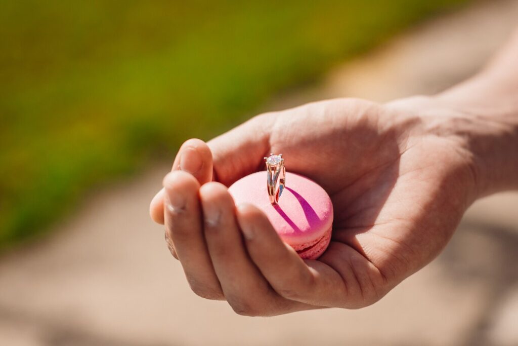 man-holds-pink-macaroon-with-wedding-ring_8353-5336